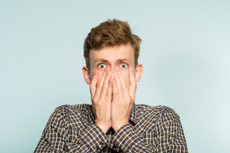 man shocked with hands over mouth